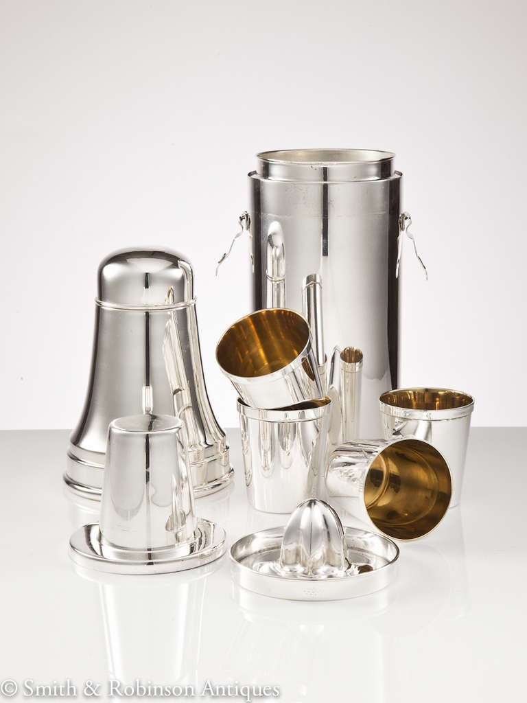 A superb quality cocktail Shaker with all it's original accessories including three spirit flasks, four shots cups and lemon squeezer, England, circa 1930.
The top is held in position with two hinged clips and the whole kit is precisely designed