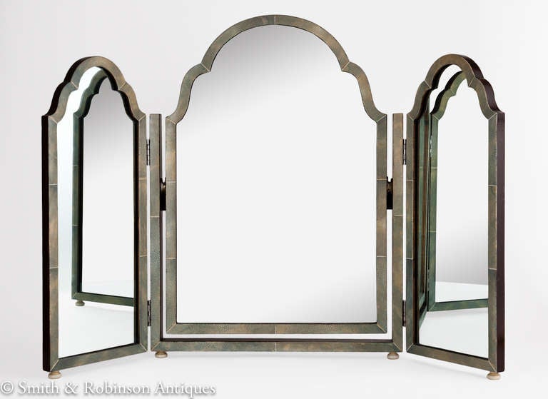 A large shagreen triple folding Art Deco vanity mirror English circa 1920.
The colour is a very muted green which also  adds to it's beauty.
It is supported on four bun feet.
It has its original plate mirrors &  the reverse of the frame is a very
