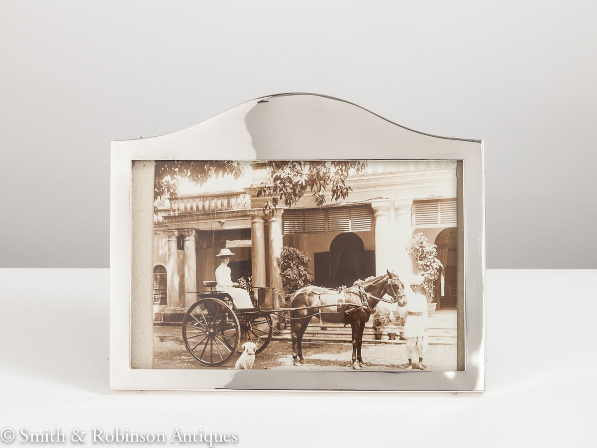 An antique silver arch-top & landscape picture frame, dated Sheffield 1925
by makers Walker & Hall 
The silver is cast & the optional colonial picture in this case adds to its overall charm.
Complete with its original oak back.

We are always