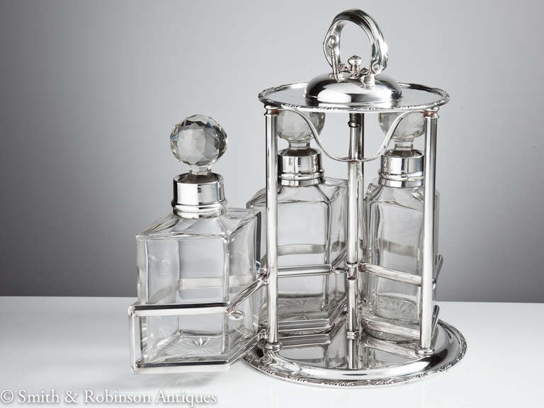 A great tantalus with bottles all dated Birmingham 1911.

An unusual key opening at the top which lifts a central rod to release the mechanism to allow the decanters to swing outwards.

The decanters themselves lean towards the Art Deco period