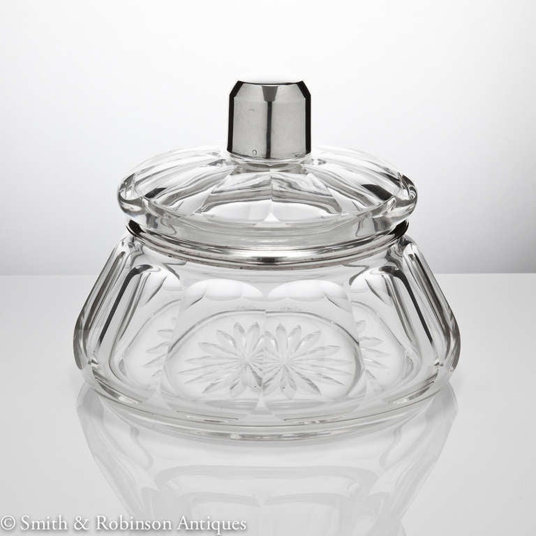 A beautiful multi-facetted art deco design realized in the finest of quality French clear glass and complete with silver mounted rim and finial, and starburst engraved base decoration.<br />
The rim and finial are both silver and date 1925-1930.<br