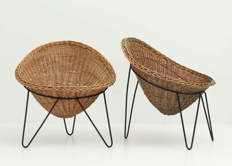 A pair of French basket chairs from the 1950s. Black iron bases and wicker basket seats.