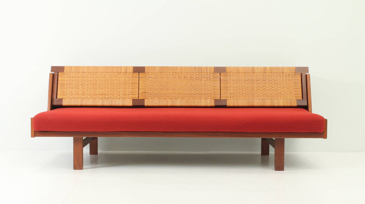 Teak daybed designed in 1954 by Hans Wegner for Danish company Getama. Teak wood frame and cane back rest that allows to displace it easily up to get a single bed. Upholstered with original wool fabric in excellent condition.
