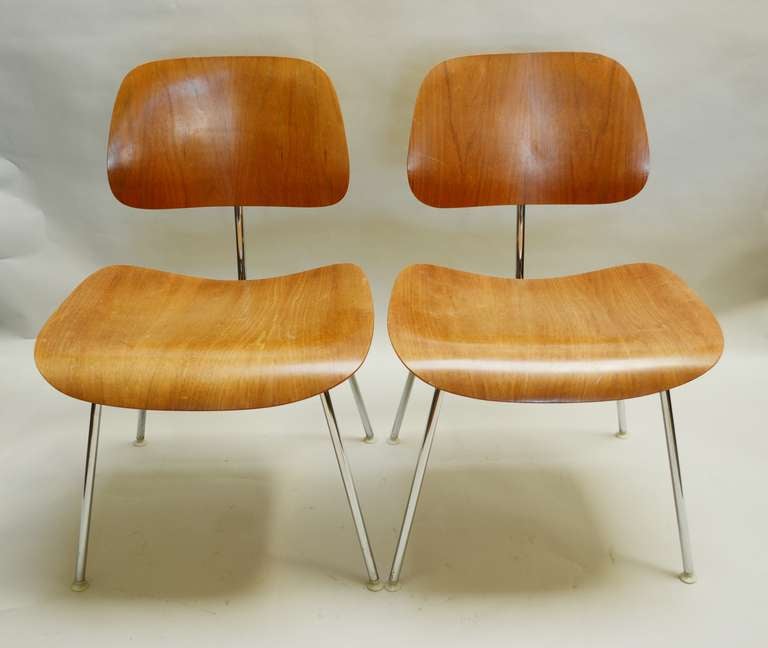 Two walnut dining chairs by Charles and Ray Eames.