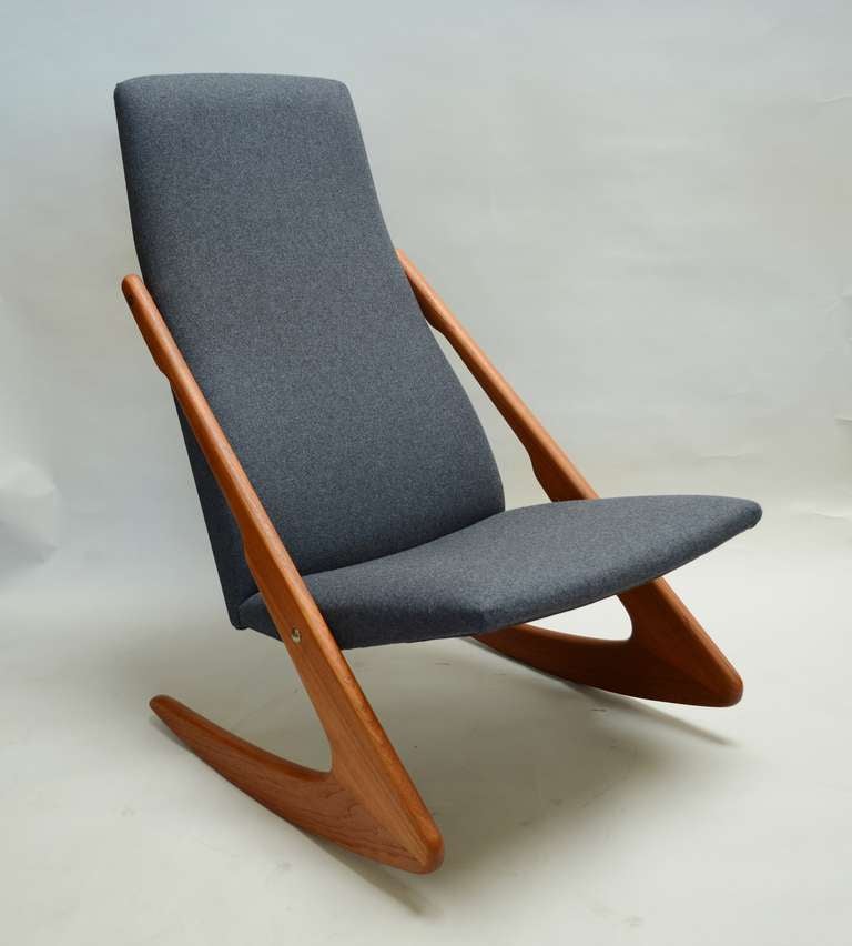 High back Danish rocking chair with dramatic teak legs. This rocker has been reupholstered with Kvadrat wool fabric. The fabric is a charcoal color with a hint of blue or violet in it.