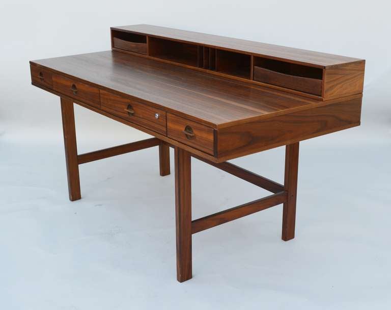 A versatile desk with a large working area that can be increased by flipping the top portion over. The desk has four drawers with one that can be locked. There is storage on the top portion as well on the back. The height of the desk work area is