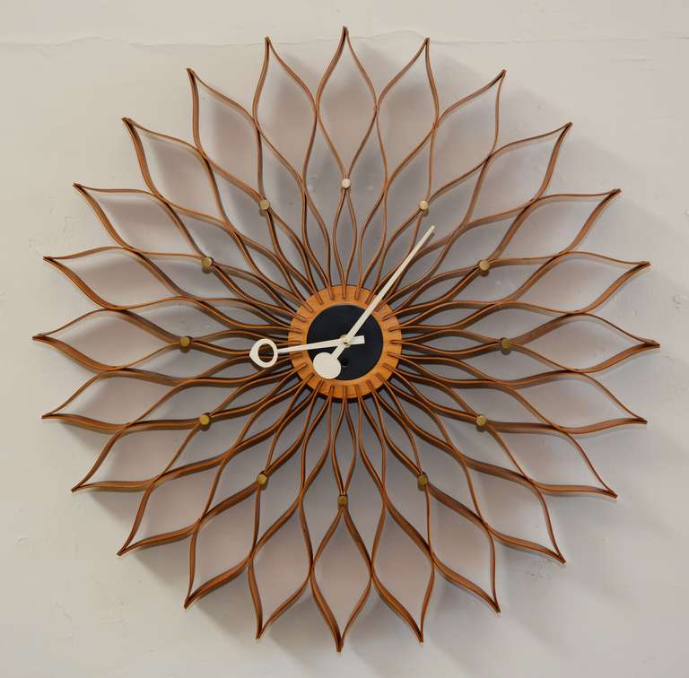 Sunflower clock designed by George Nelson and Associates for Howard Miller. The petals on this clock are a combination of walnut and birch veneers. This was originally had a key wind mechanism but it was replaced at some point with a quartz