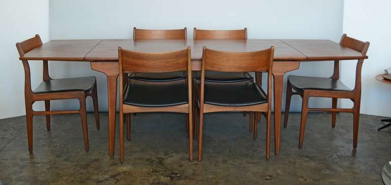Walnut extension table with six side chairs by Funder-Schmidt & Madsen. The top of this table is boat shaped, tapering at the ends. The table base and chairs are solid walnut construction. The table and chairs are in original condition and show very