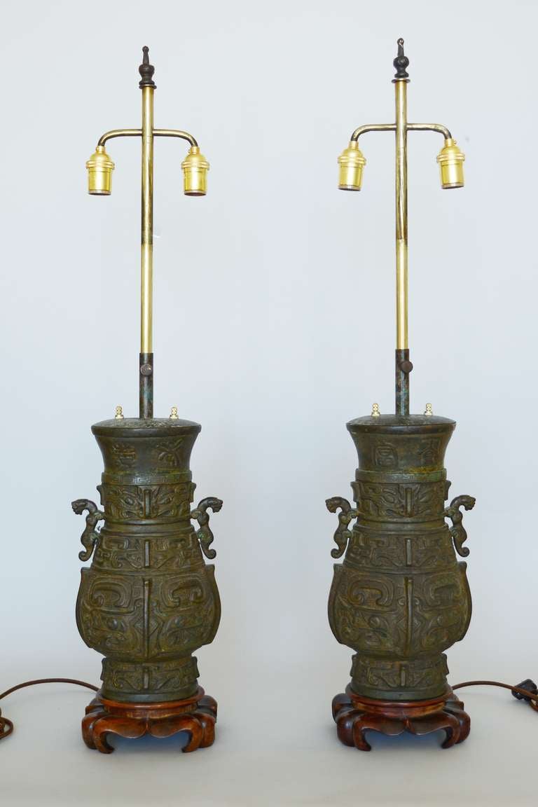 Pair of Asian style table lamps in the form of bronze urns. The bronze castings on these are substantial and heavy. These have  new sockets and switches and been rewired with brown rayon cord. The height is adjustable from 30 to 38 inches.
