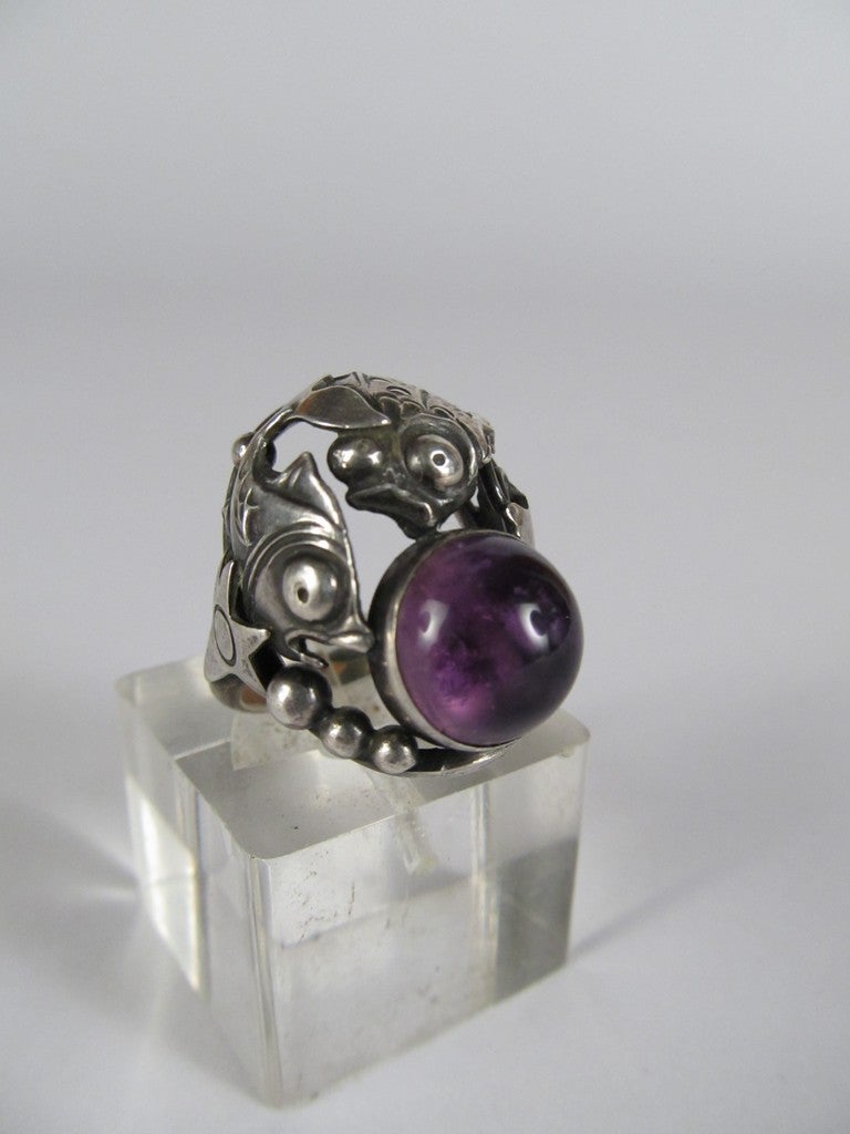 This unusual figural ring was made by Danish jeweler Nils From, circa 1950's.  Two sterling fish are encircling an amethyst cabochon, and both sides are flanked by a starfish.  