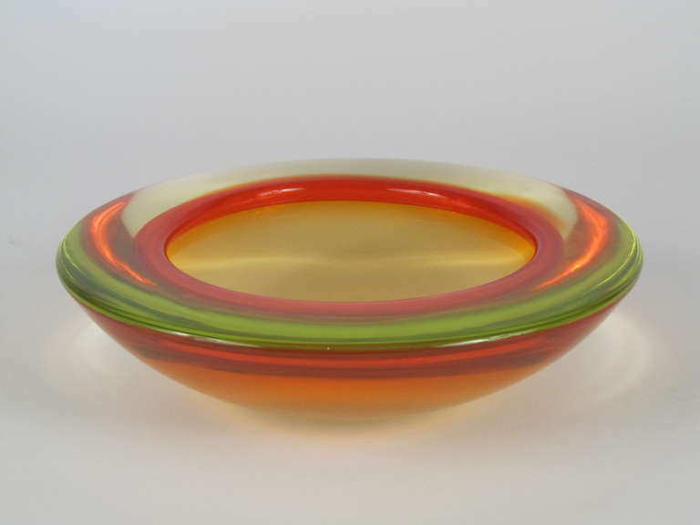 The striking contrast between the fluorescent green body of this bowl and the bright red rim make this piece a real eye catcher!   It has a very sleek and modern design, with a striking profile, and the contrasting colors dance around the shape as