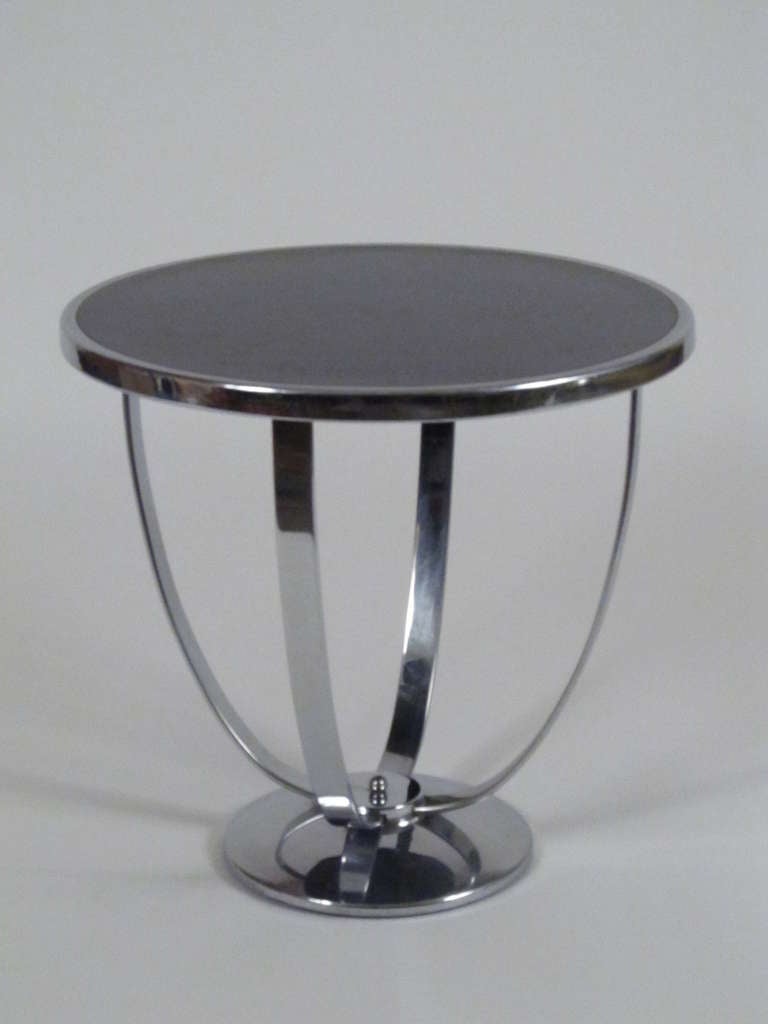 This is a lovely and gracefully styled side table made by Howell Furniture in the 1930's. The upward supports are flat chrome, and the gentle arc of these are echoed by the curve of the domed chrome base. The top is black formica. A small brass tag