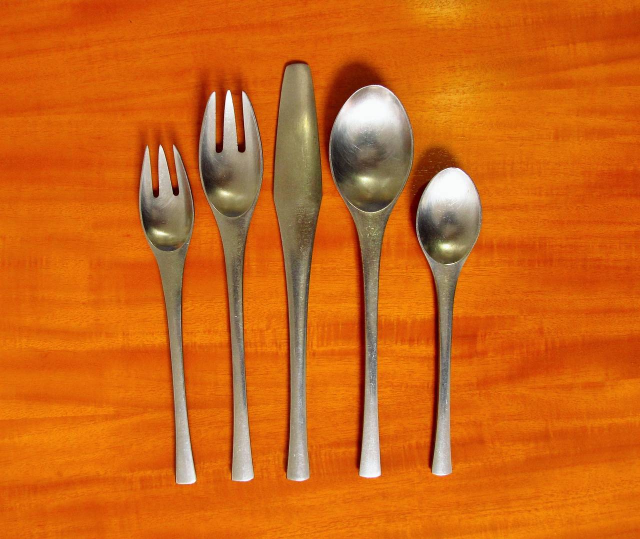 Jens Qvistgaard designed set includes eight dinner knives, eight dinner forks, eight salad forks, eight soup spoons, eight tea spoons, salad server set, one serving spoon, salt and pepper, Designed in 1958. All of these pieces are marked 