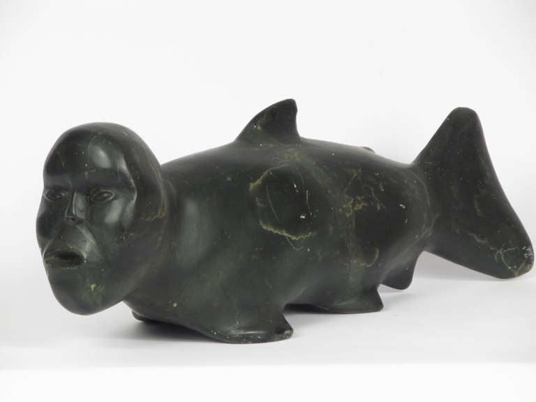 This is an exceptionally large, and culturally significant work of Inuit stone carving art.  It measures 19 inches in length.  It illustrates the reverence for the source of the subsistence for the Inuit people.  The head of a man.  The body of a
