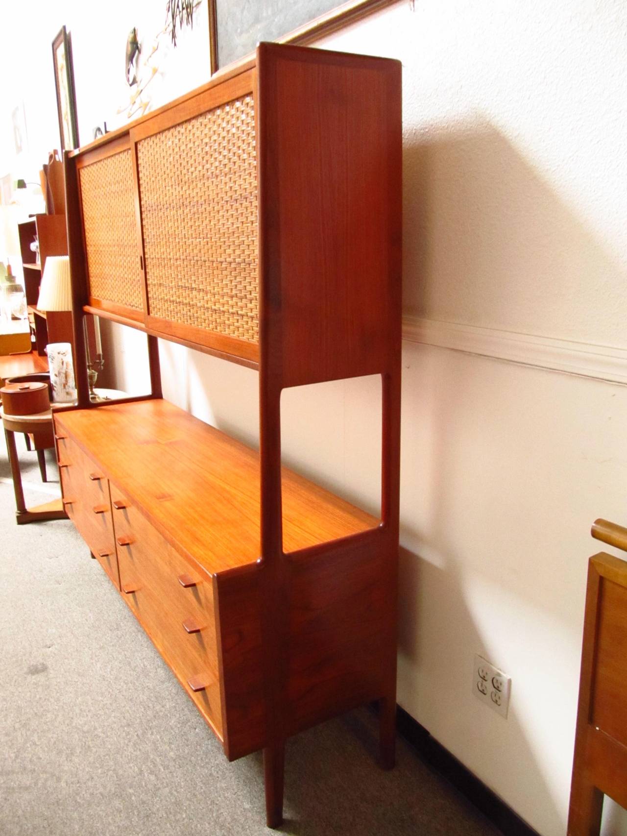 This is a truly striking piece of furniture. It's a somewhat rarer version because of the contrasting caned doors on the top. Two sliding doors reveal a beautiful blonde interior with a total of five shelves. The six drawers have rosewood tab