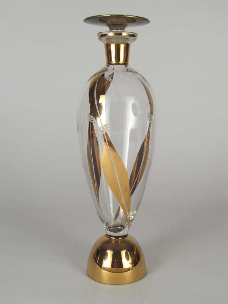 Elegantly stylized glass decanter that is decorated in gold overly and etched accents.