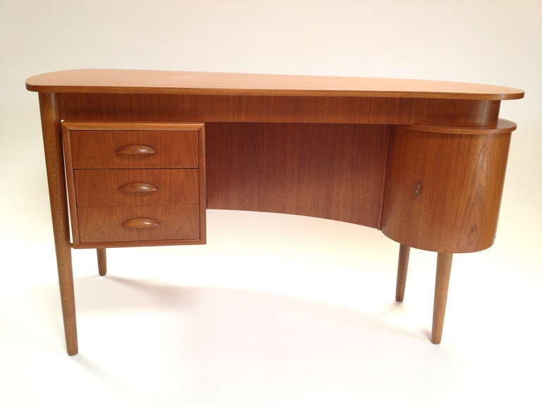 Unique Danish Modern Teak Kidney Shaped Desk with Bookcase and Storage.  Exceptional and functional design with a small footprint!  Front features bookcase storage area as well as a small cabinet.  Excellent condition.  Note desk has a slightly