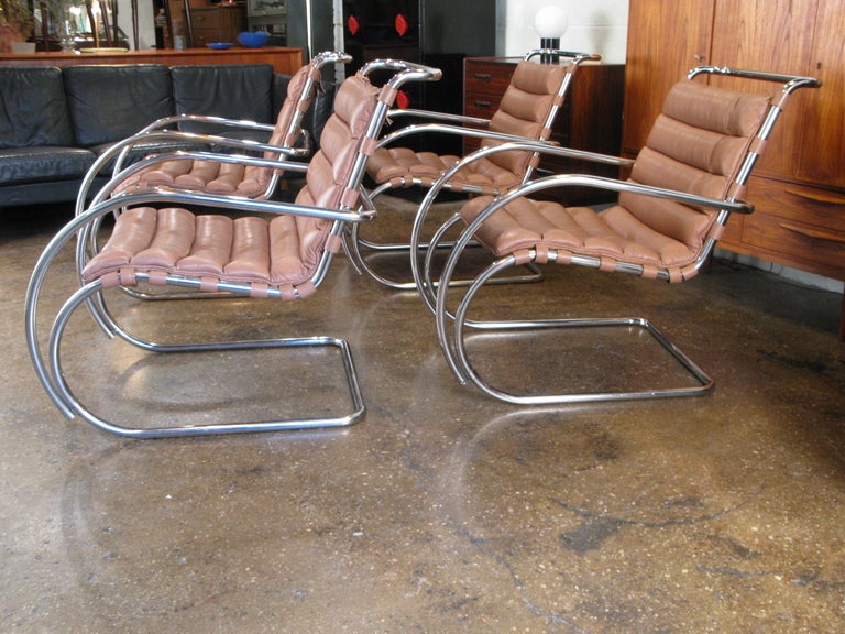 Amazing mid-century style for the home or office! Set of four MR armchairs feature channel-tufted leather cushions and serpentine stainless-steel frames. Seats are firm and tight; the original leather is soft, with a nice broken-in suppleness. All