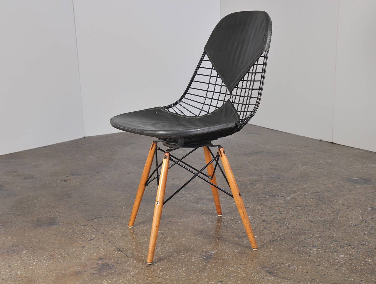 Rare find: early Eames for Herman Miller wire chair on a swivel dowel base in all-original condition. This chair is just dripping with authentic patina, from the oxidized screws to the age spotting on the dowels and wear on the wire mesh. Bikini pad