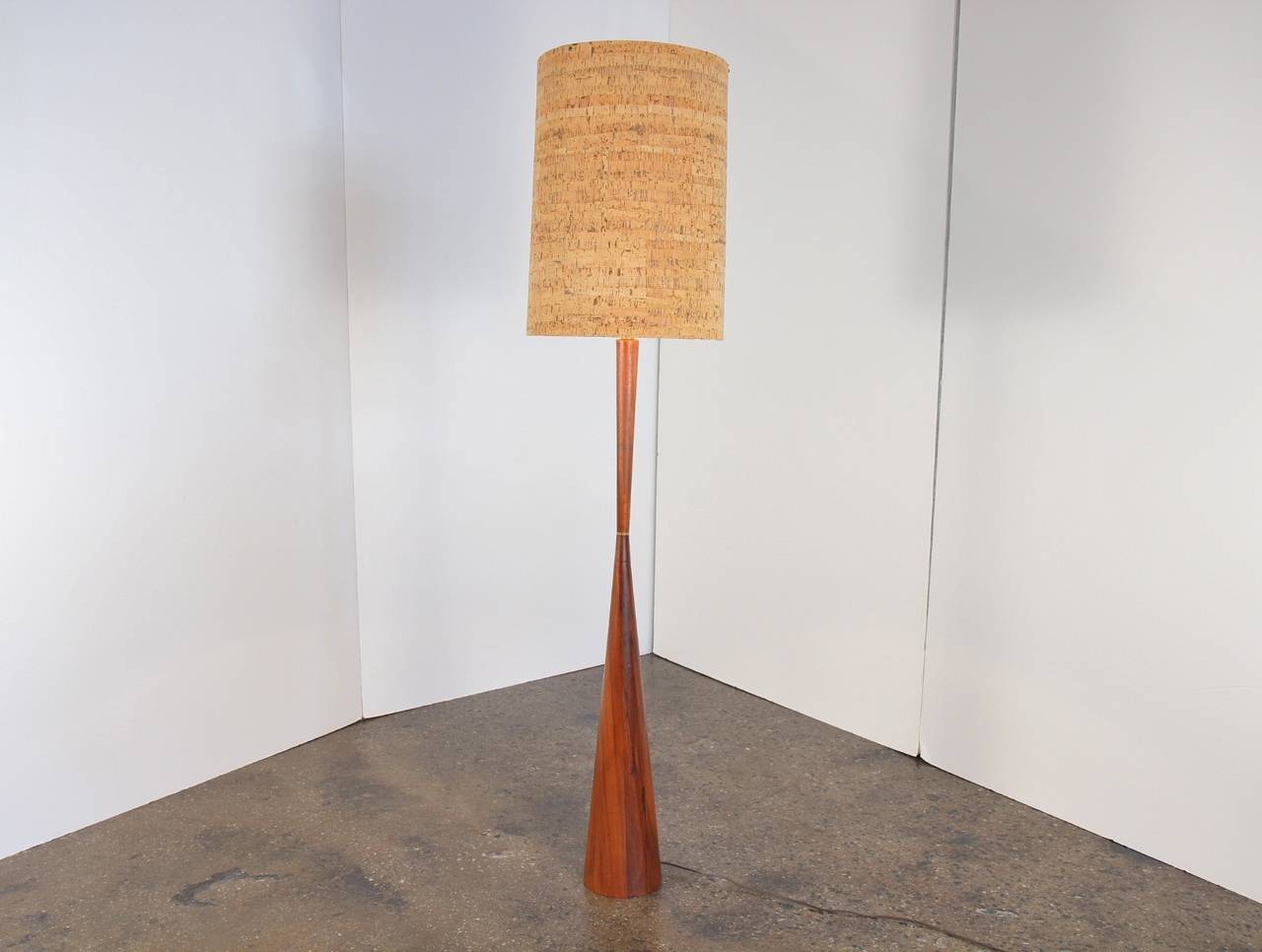 Large walnut floor lamp sports an amazing original cork shade. Brass detail is a nice touch, highlighting the tapered wood base, which is in the style of Phillip Lloyd Powell. 1950s. In excellent vintage condition.

65.5