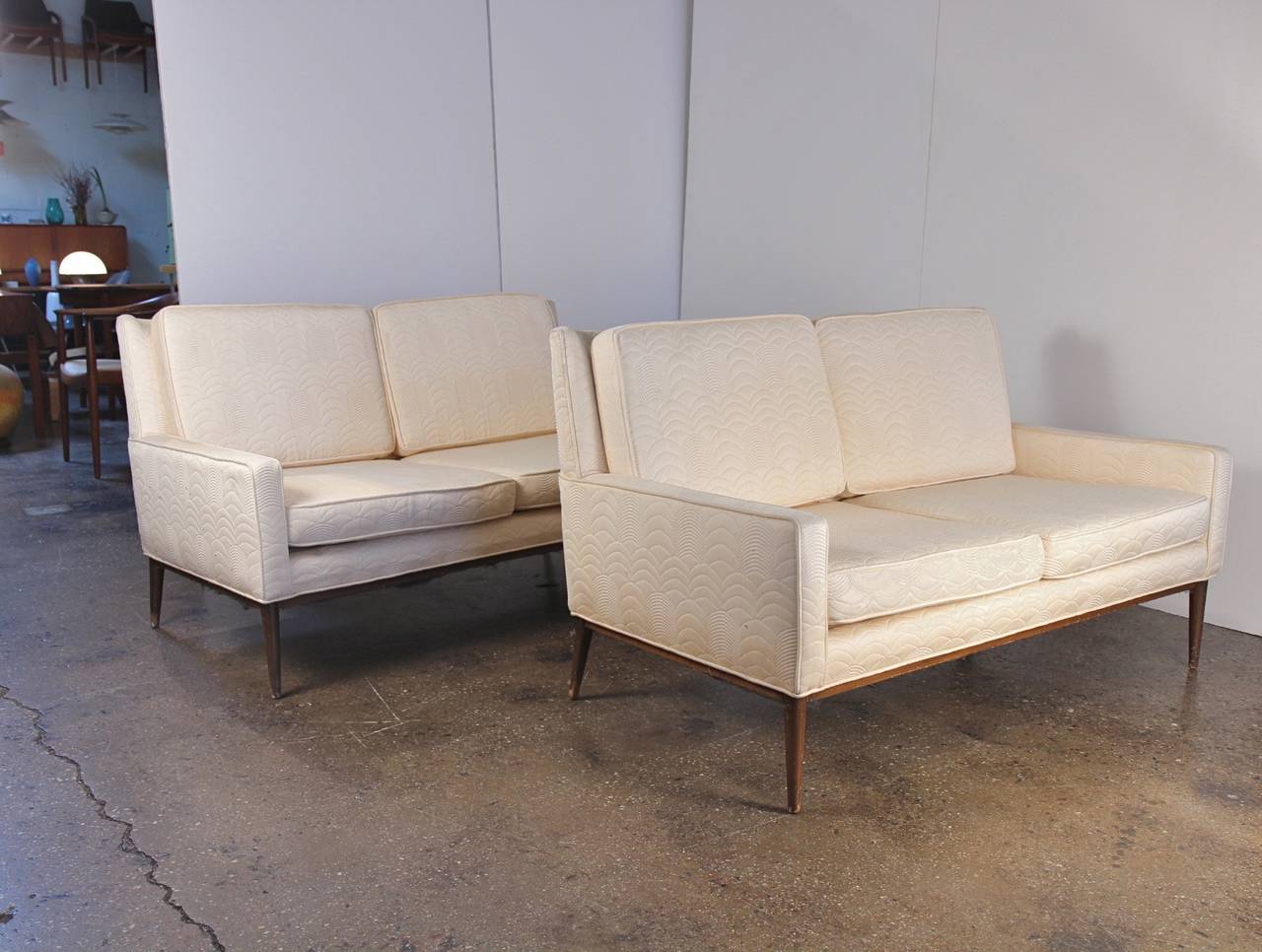 ONLY ONE LEFT. We have two of these lovely mid-century small sofas designed by Paul McCobb. These matching love seats are covered in the original amazing quilted cream fabric, which has wear. Use as-is or ask us for an upholstery quote. Sturdy and