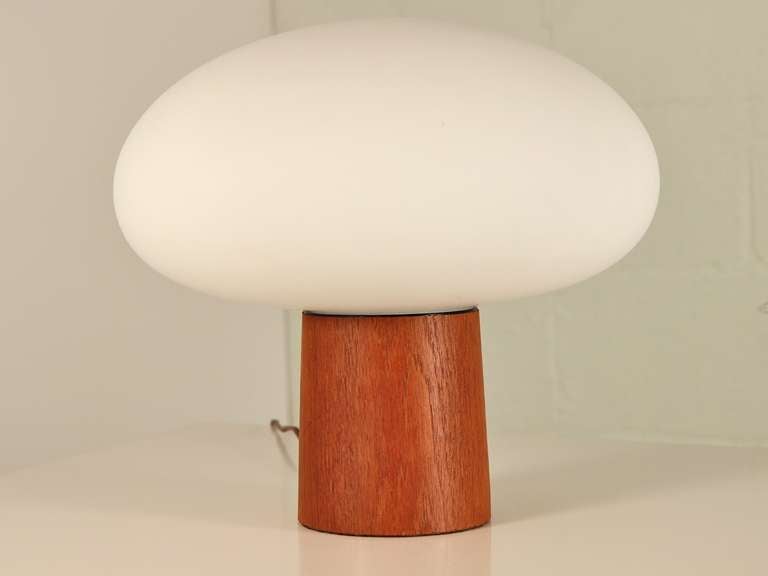 Highly collectible Laurel lamp has a round teak base and a frosted glass shade. This table or accent lamp provides a lovely diffused glow. 1960s. In excellent vintage condition. Marked Laurel Lamp Co.

Lamp is 12