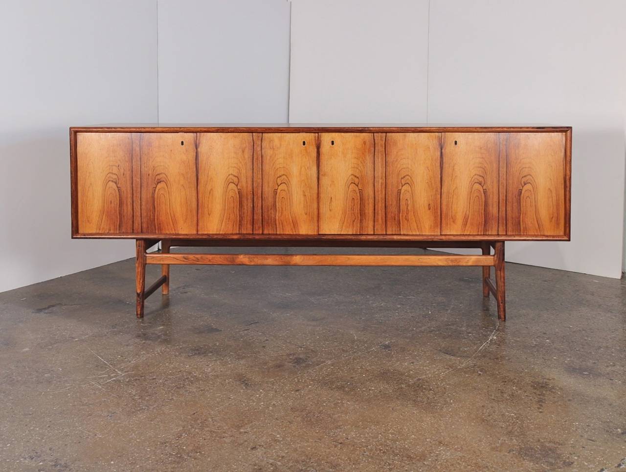 Stunning rosewood credenza features incredible wood selection and an elegant, minimal design. Four doors lock with keys, open to reveal adjustable shelves and five drawers for tons of storage. The back is finished so the sideboard can float in the