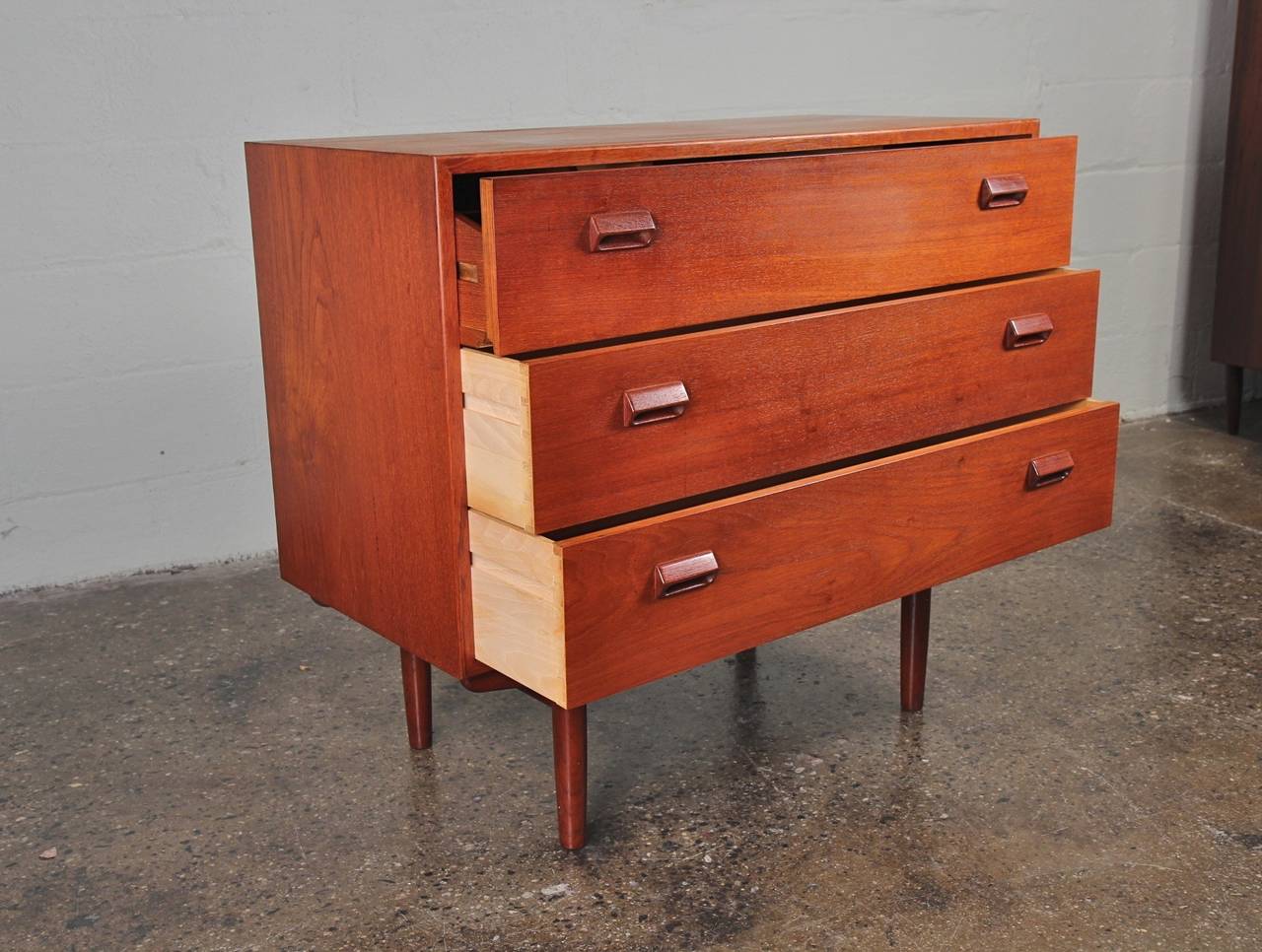 Lovely Danish modern teak vanity. The top drawer opens to reveal storage and a pull-out mirror. There are two more standard dresser drawers below. We have additional matching storage pieces that form a suite: a tall boy and a four-drawer dresser.