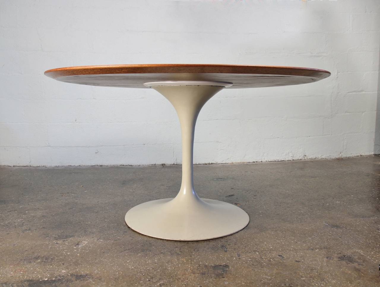 Pedestal table designed by Eero Saarinen for Knoll dates to the 1960s. Gorgeous round walnut top on a white powder-coated pedestal. The dining table comfortably seats six. In excellent condition; the wood top shows very little wear and has beautiful