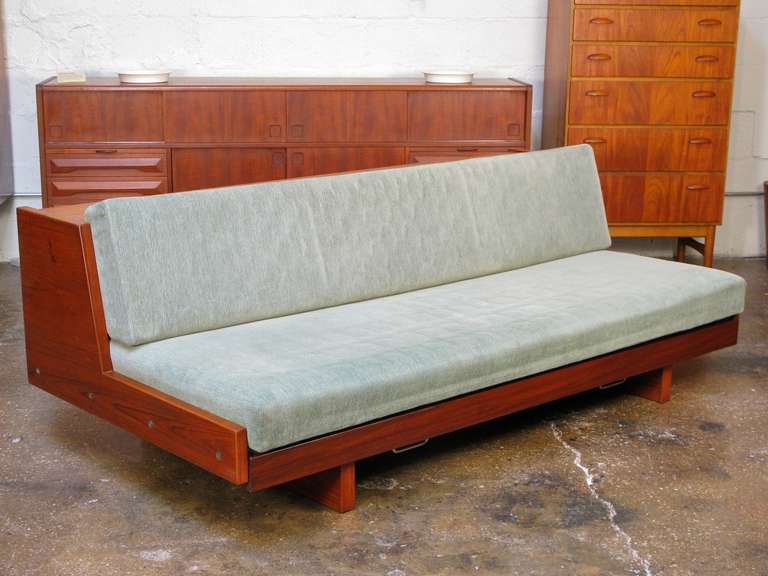 Spectacular teak-framed sofa by master Danish designer Hans Wegner. This rare version of his famous daybed has a base that slides open to create a larger (double) bed. A bed cover unrolls to protect the cushion. Made of teak, beautifully restored.