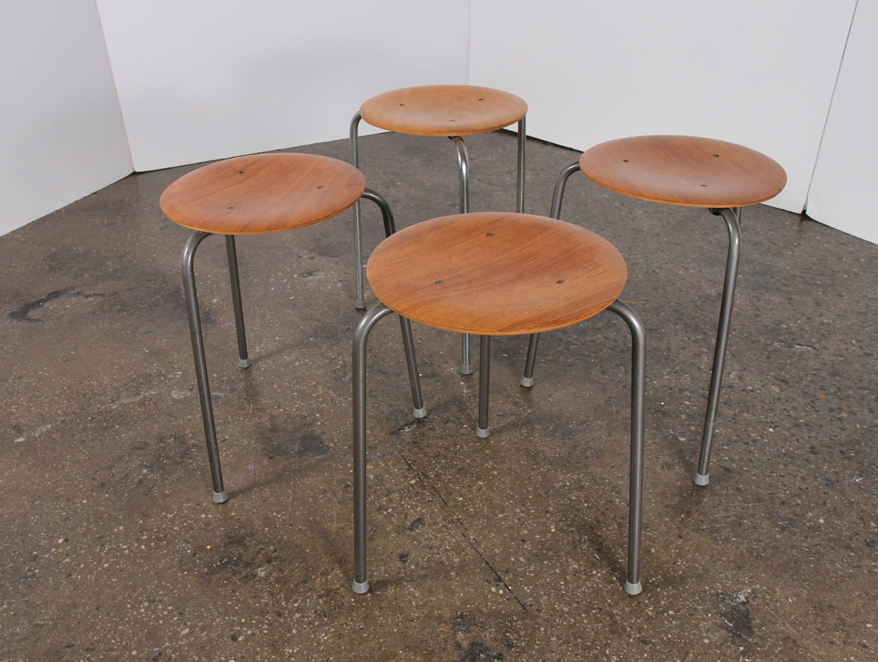 Set of four molded teak stools stack easily and brim with Scandinavian style. Designed by Arne Jacobsen for Fritz Hansen, circa 1950. The stools function nicely as occasional tables as well as seating. They have a lovely patina. Marked 