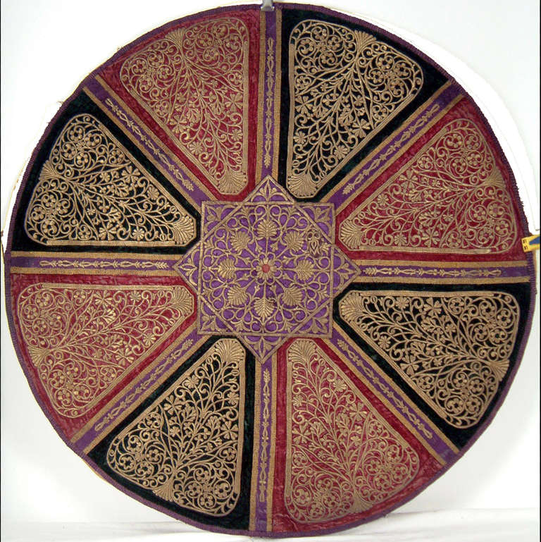 Rounded form.

Eight triangle cartouches  embroidered with gold thread forming palmettes.

An eight point arab star in the center.