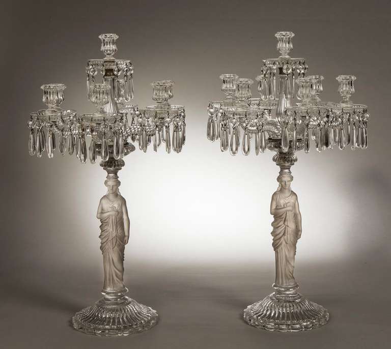 Each with a beaded and lobed urn socket above a dished drip pan hung with pendants, on a lobed baluster stem above six conforming sockets and drip pans on twist moulded arms, rising from a lobed fitting above a standing caryatid portrayed draped in