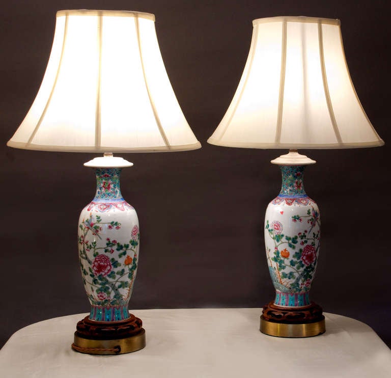 Pair of baluster form lamps in the floral Famille Rose palette, hand decorated in polychromes with foliates and birds.