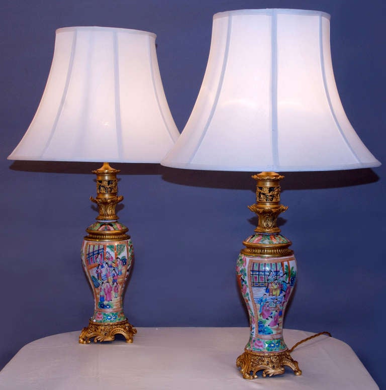 Belle paire de lampes de forme balustre décorées à la main en polychromie de scènes de cour, montées sur des bases rococo en bronze doré.