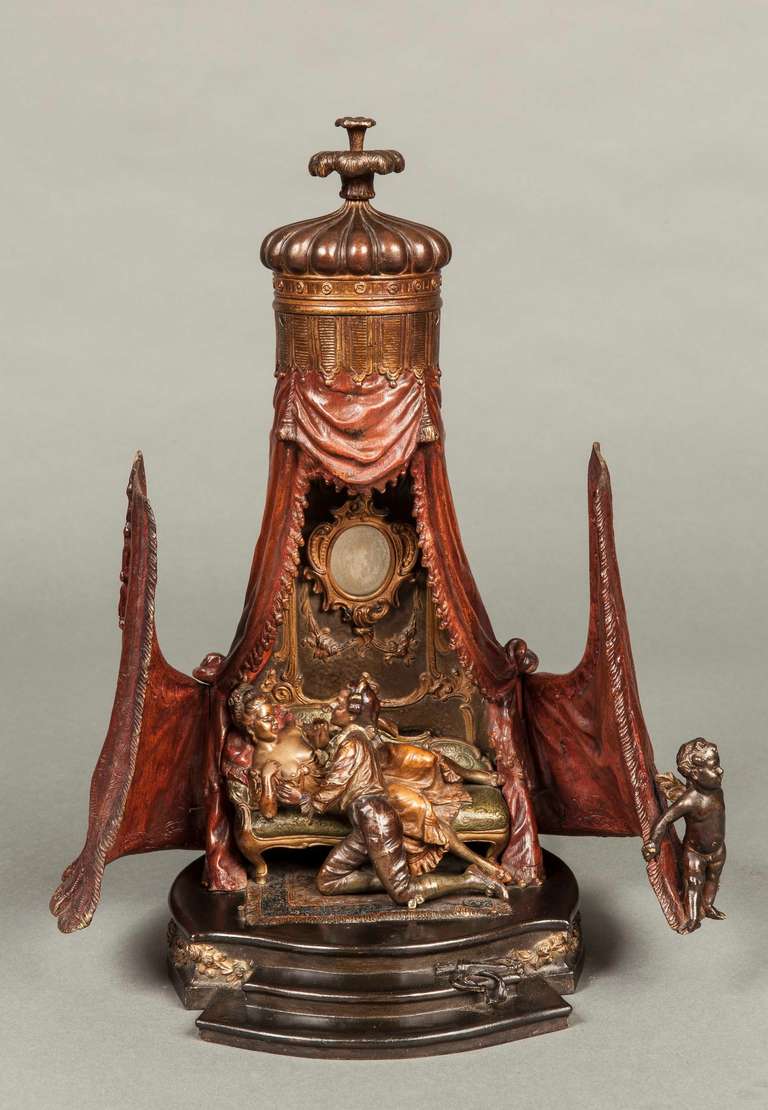 Le bronze peint à froid représente une tente fermée, avec des doubles portes à bouton, l'une avec un cupidon au sourire narquois, qui s'ouvre pour révéler un jeune homme courtisant ardemment une femme légèrement vêtue et confortablement drapée sur