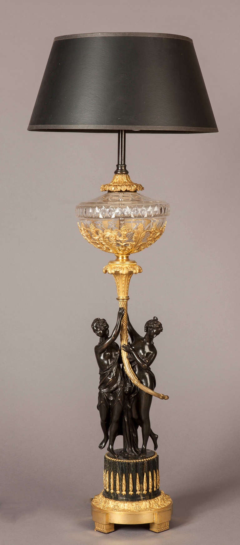 French Banqueting table lamp signed by Georges Viam

Constructed in gilt and patinated bronze and a cut glass oil reservoir; rising from a bracket footed floral cast and chased circular base, bearing the maker's signature, with a fluted circular