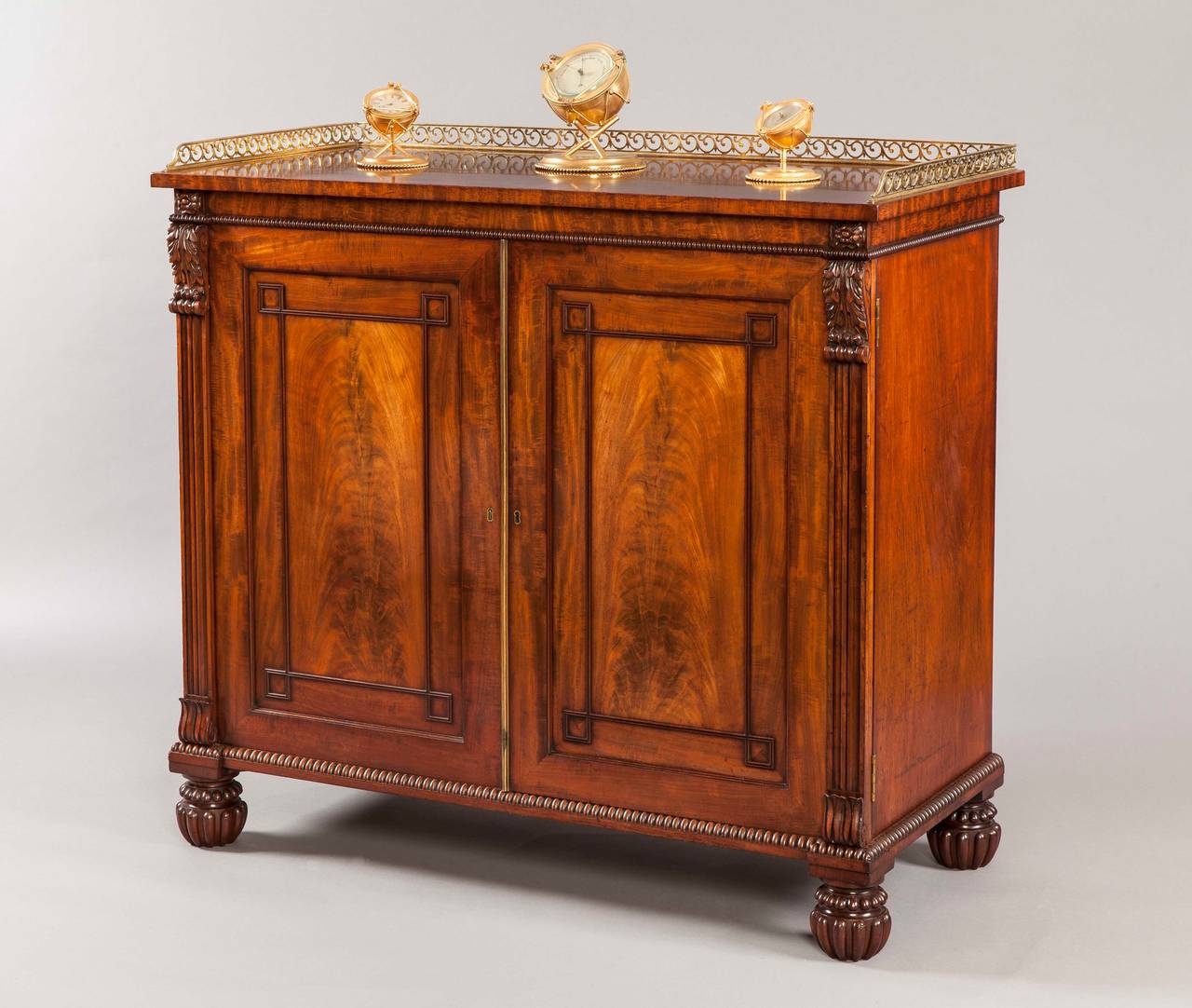 A late Georgian side cabinet firmly attributed to Gillows of Lancaster

Constructed in a finely grained Cuban mahogany; rising from ring turned and lobed oblate bun feet: over, housed between two stiles having stylized carved lotus leaf bases and