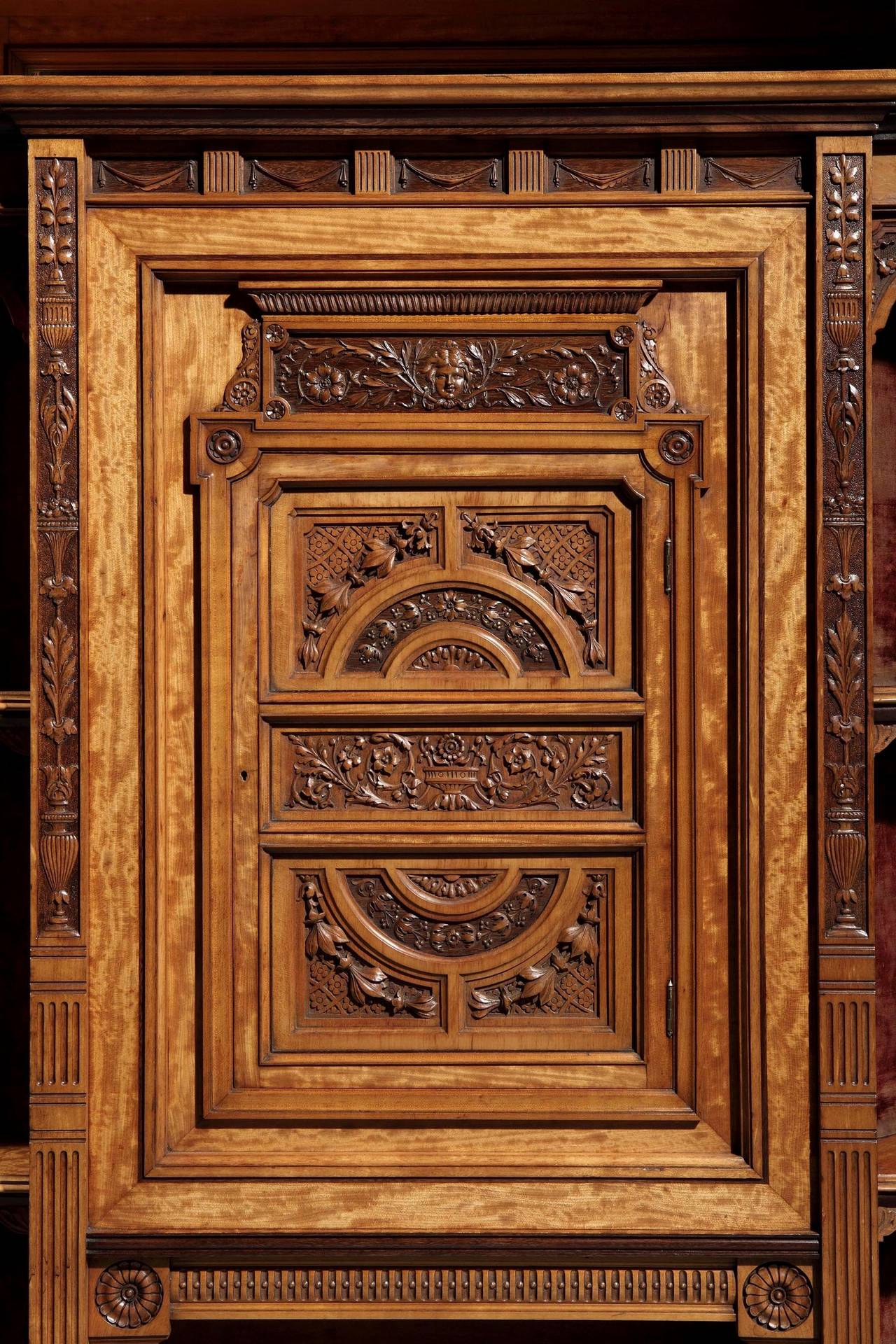 A magnificently carved display cabinet of exhibition quality.

The maker has chosen to use a richly grained satinwood and executed the carving with extraordinary fluency and precision, foliates, putti and birds are featured; over the open