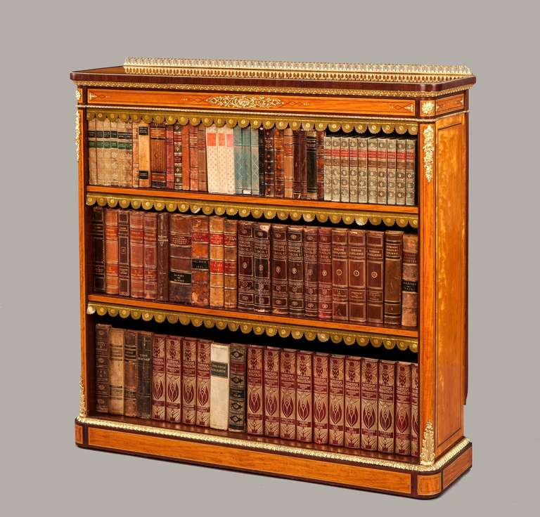 A fine open bookcase in the Manner of Holland & Sons

Constructed in a finely marked and patinated satinwood, having amaranth cross bandings, and exotic wood marquetry inlay, dressed with high quality gilt bronze mounts; rising from a plinth base,