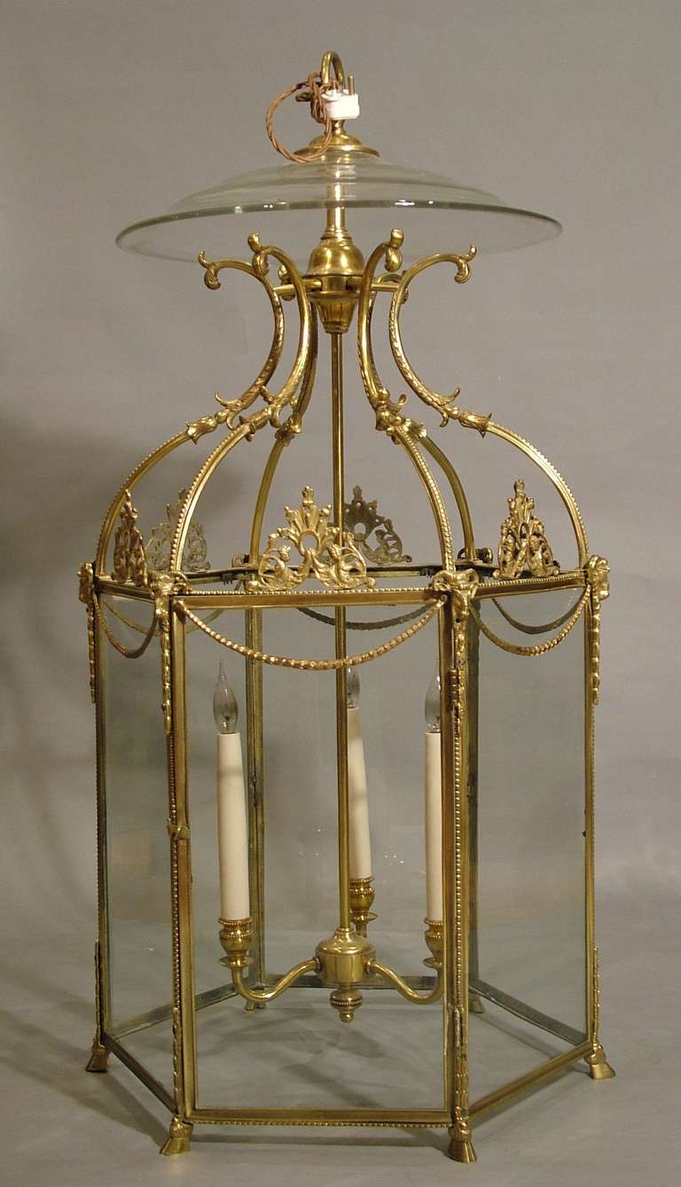 A fine hall lantern in the neoclassical Adam Manner
Constructed in bronze, of hexagonal form, containing a central column issuing three arms, with ‘s’ form faux candleholders; each pillar capped with ram heads, with a running bead design to the