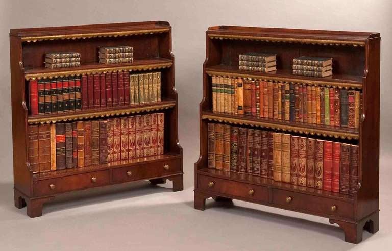 A pair of Mahogany dwarf open bookcases

In the Regency Style, each with half gallery and three stepped shelves and containing two drawers, on bracket feet.