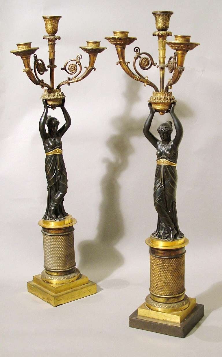A Good Pair of Empire Candelabra In the Manner of Percier & Fontaine 

Using patinated and gilt bronze, the engine turned barrel plinths being set onto square section bases, with winged and draped female figures in the Grecian taste over, standing