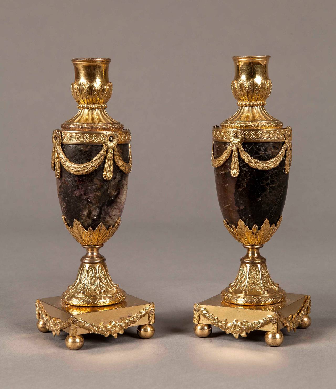 A pair of Blue John Cassolettes by Matthew Boulton

Constructed in gilt bronze and Derbyshire Blue-John fluorspar; the square bases are supported on ball feet, the ovoid bodies enwrapped with swags and garlands, with conical covers; reversible to