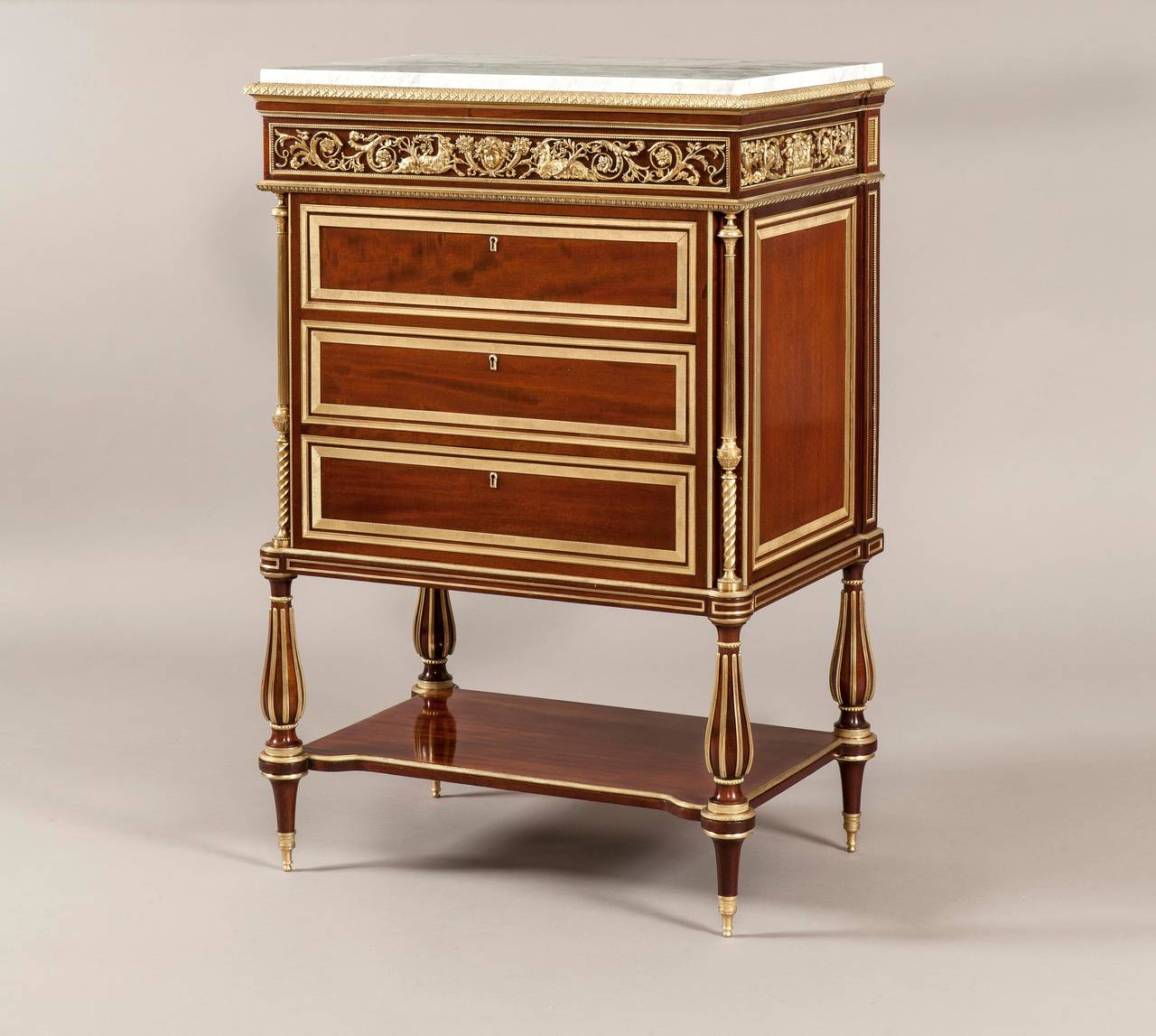 Pair of Commodes In the Manner of Adam Weisweiler

of rectangular form, constructed in mahogany, dressed with Fine bronze mounts and brass inlays; rising from tapering and turned toupie feet, the baluster form legs are brass inlaid, having ormolu