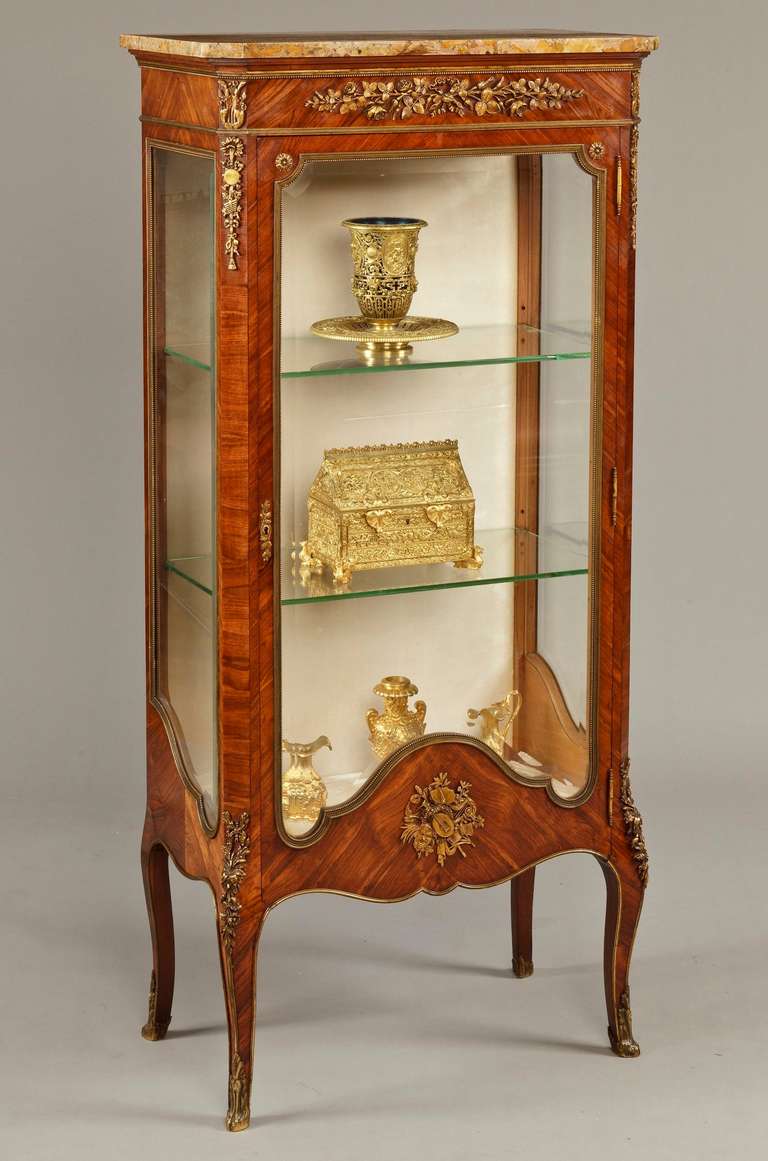 A fine vitrine in the manner of Francois Linke 

Constructed in kingwood, with gilt bronze mounts, in the Louis XVI Transitional style; rising from bronze foliate sabots, with gently swept cabriole legs capped with bronze espagnolettes; the single
