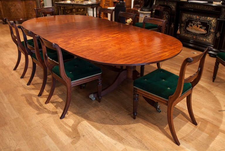 A Georgian period dining table.

Constructed in a well patinated Honduras mahogany; the three pillar supports having tripartite swept legs, dressed with brass toes and castors, with turned ‘gun barrel’ circular columns; the table having radiused
