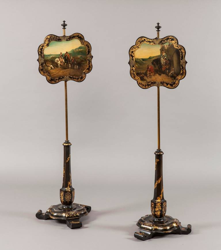 A pair of pole screens. 
Attributed to Jennens & Bettridge. 

Constructed in papier mâché, decorated with gilt arabesques and mother-of-pearl; rising from serpentine swept circular bases supported on scrolled feet, from which rise hexagonal