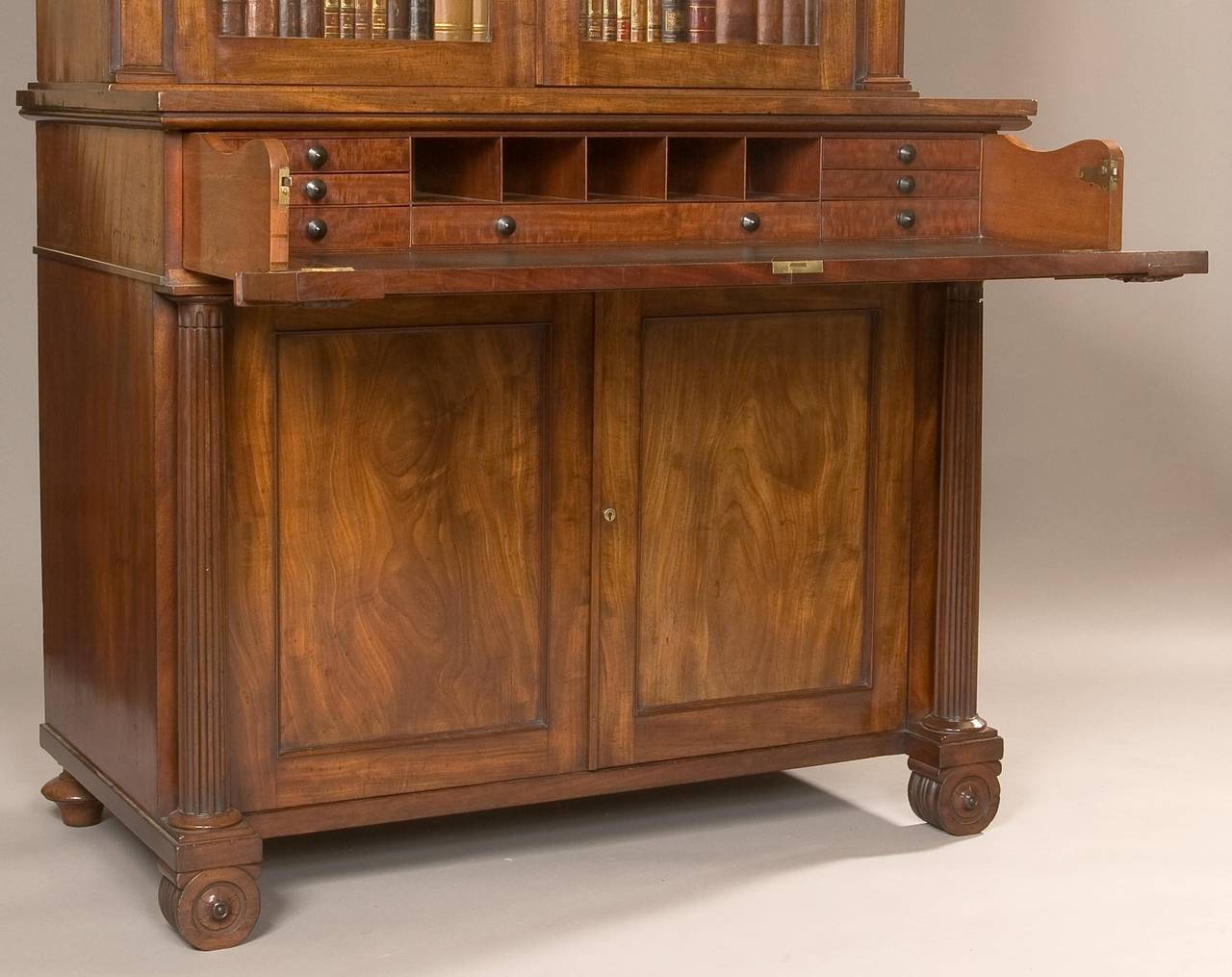 A good Regency secretaire bookcase.

Constructed in mahogany, rising from feet of circular form, the lower section having two blind doors with fielded panels, enclosing a shelved interior, and flanked by reeded columns having arcaded capitols. The
