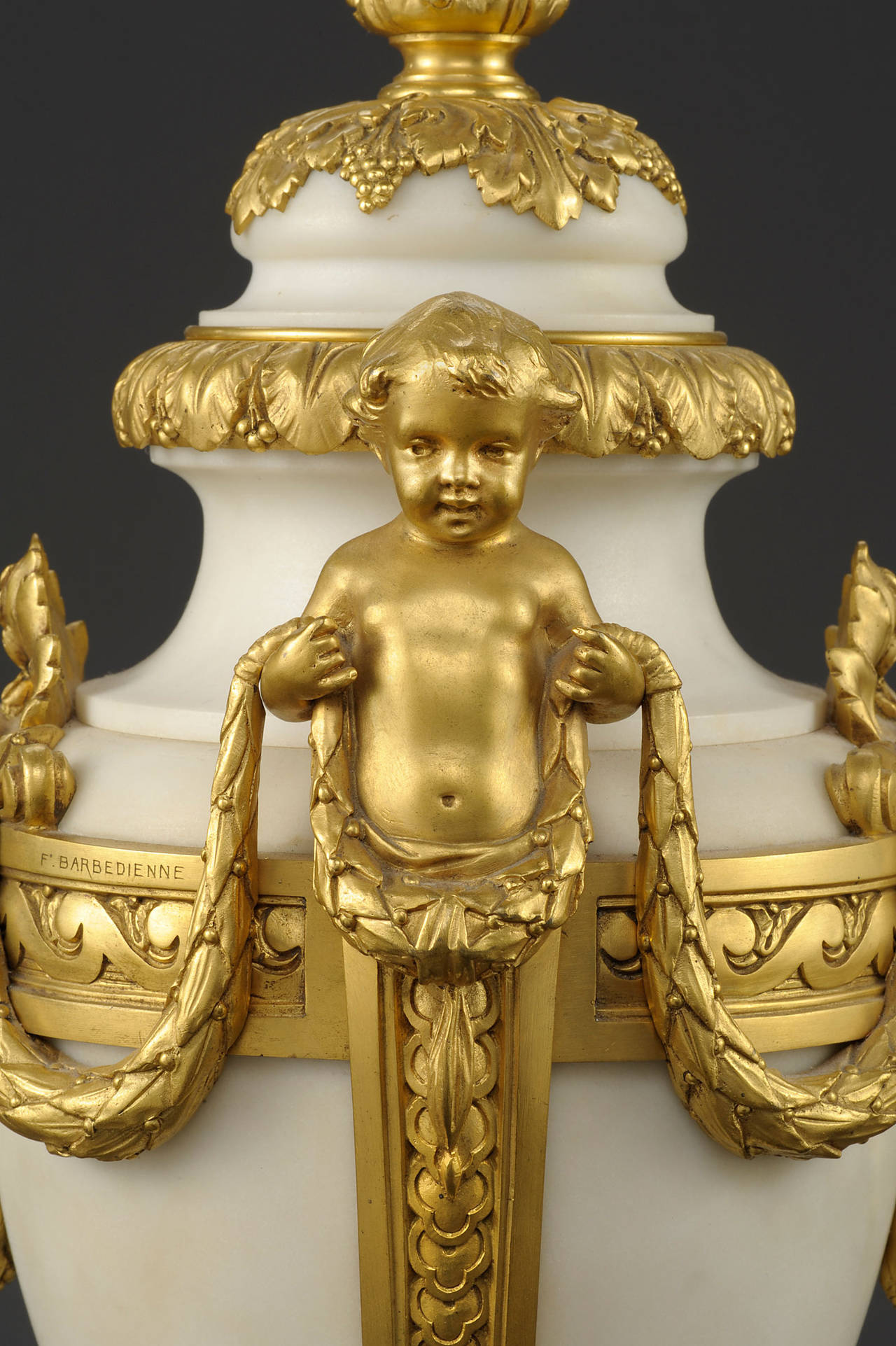 A pair of urns in the Louis XVI manner signed by Ferdinand Barbedienne

Constructed in carved white Carrara marble, and ormolu; rising from square stepped bases, the baluster form urns dressed with running laurel leaf bands in ormolu: addorsed